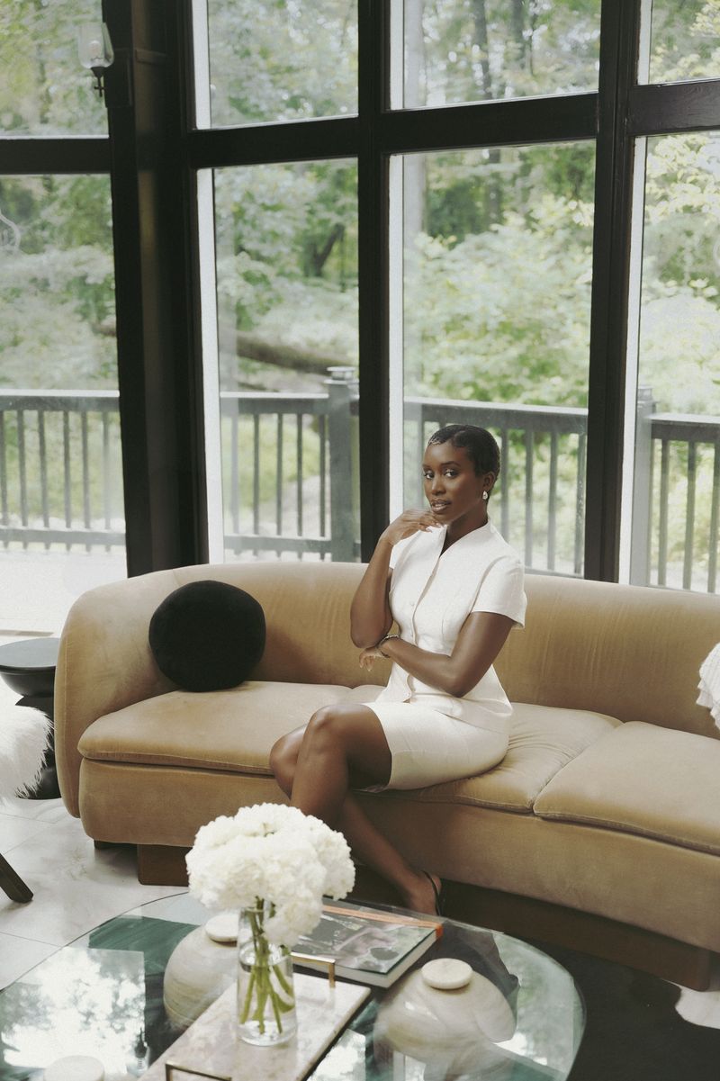 Yvonne Eseonu seated on a camel velvet sofa in a sunlit Atlanta living room